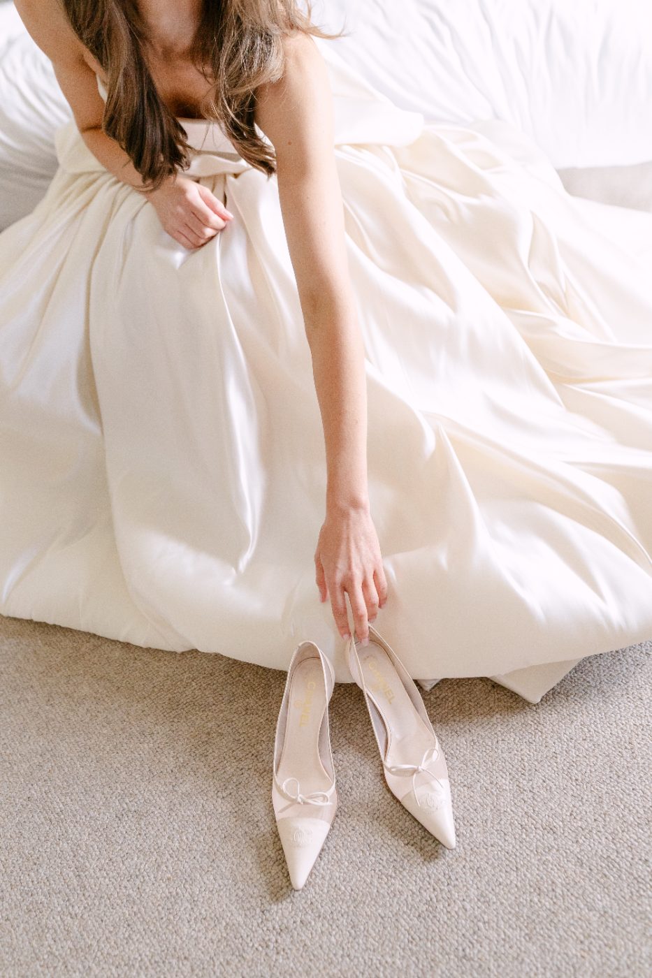 A bride in an ivory gown reaching for her heels